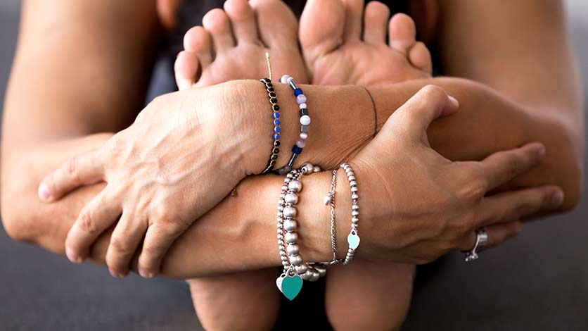 A person's armas wrapped around the soles of their feet in a yoga pose.