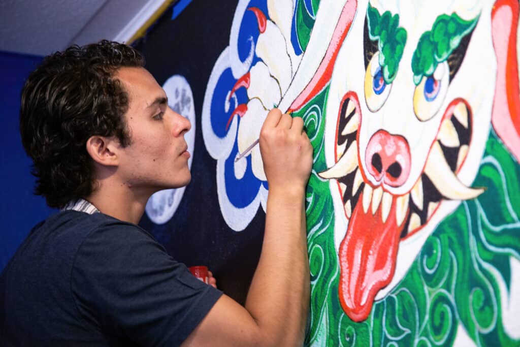 Juan Pablo Fernndez Garc painting a mural in naropa's Little Lama Cafe